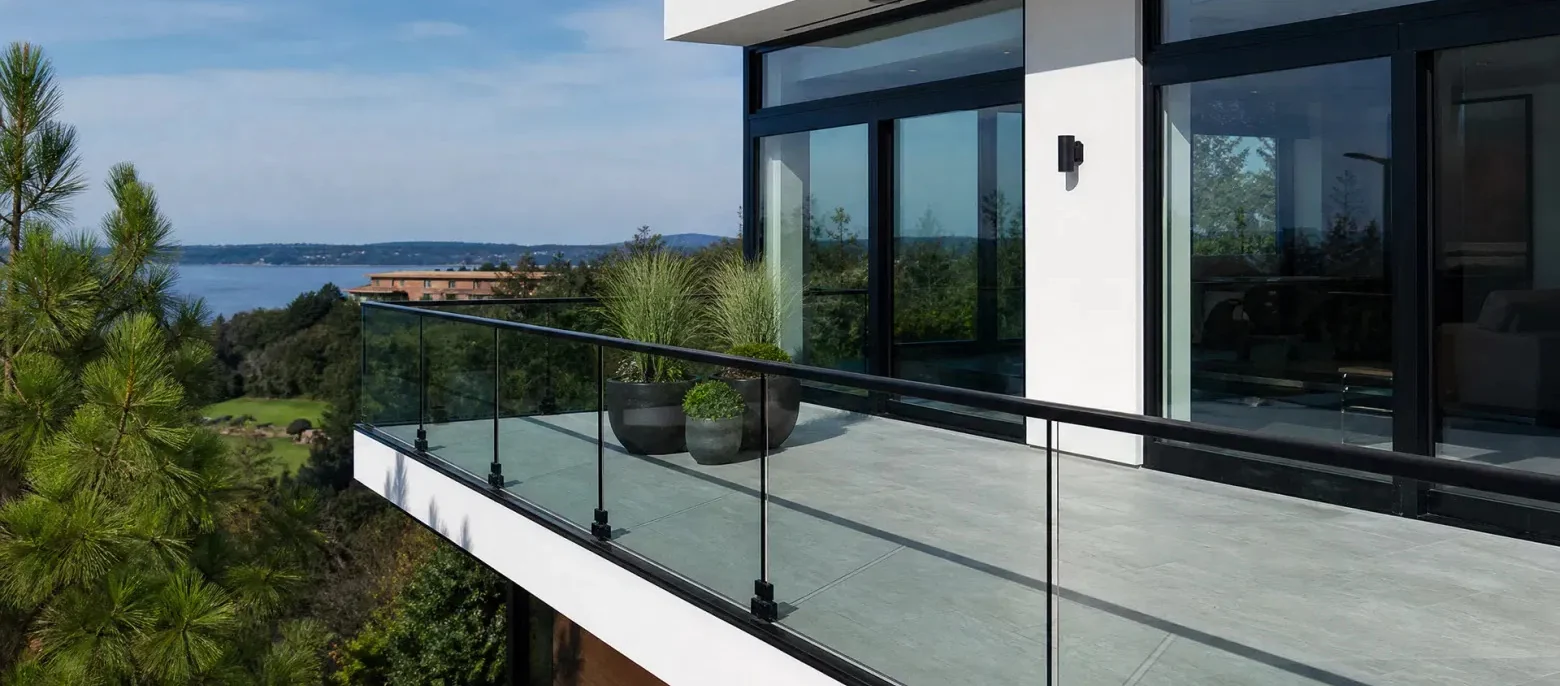 Terraço residencial com guarda-corpo de vidro e esquadrias de alumínio escuras