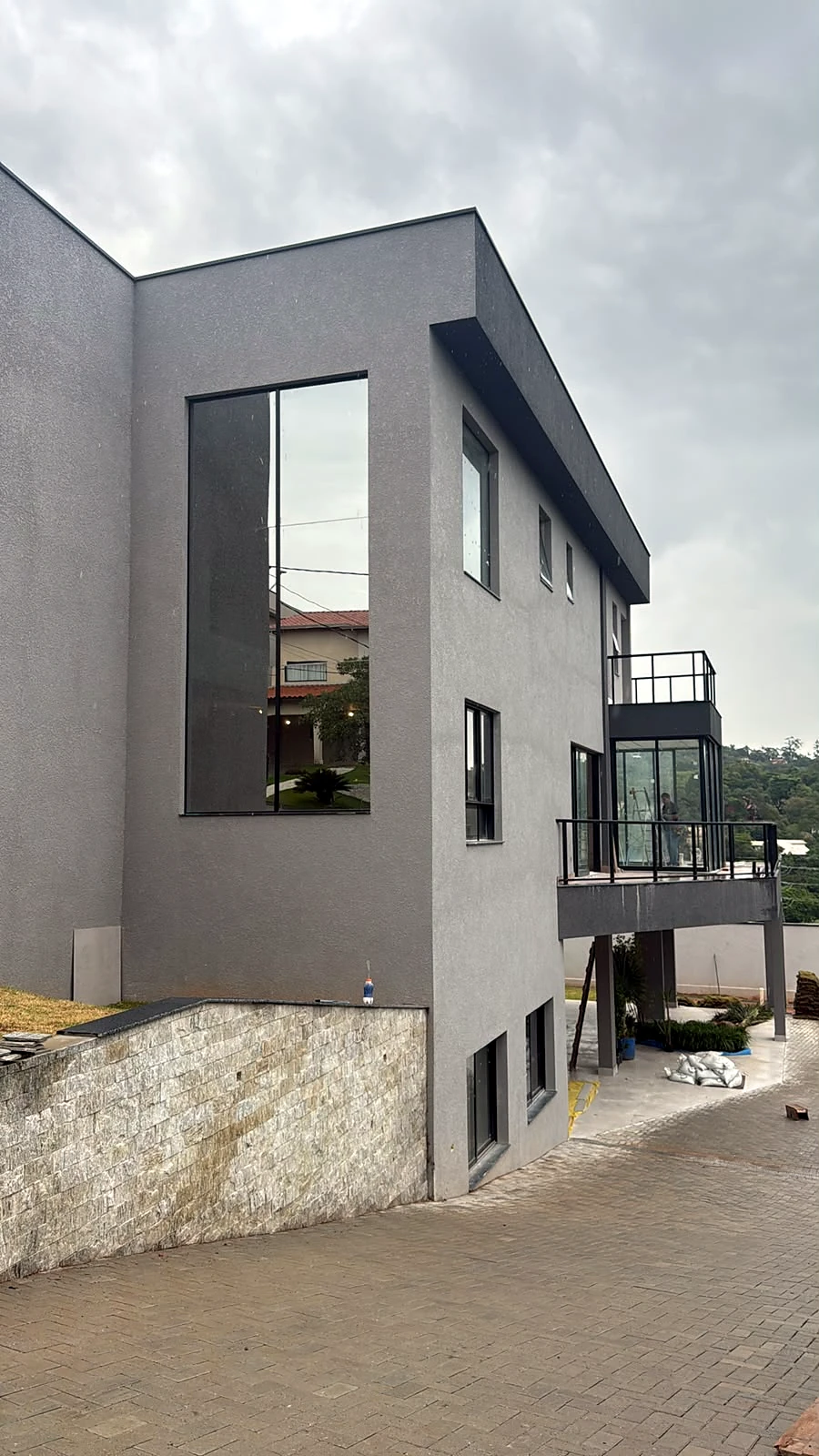 Fachada residencial com esquadrias escuras e vidro, obra da Salumin